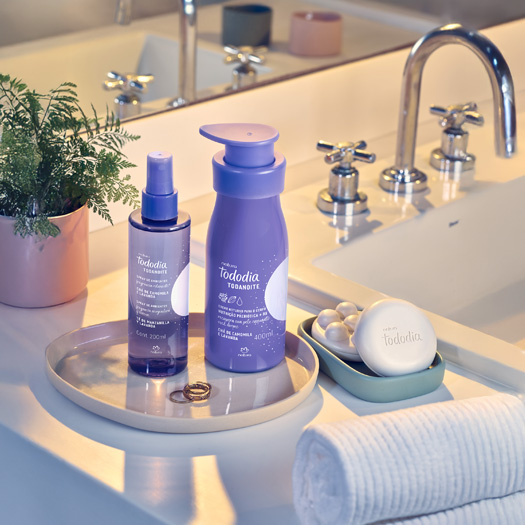 Foto de uma bancada de banheiro, com produtos Natura Tododia Todanoite, como Body Splash, Loção Hidratante e Sabonetes.