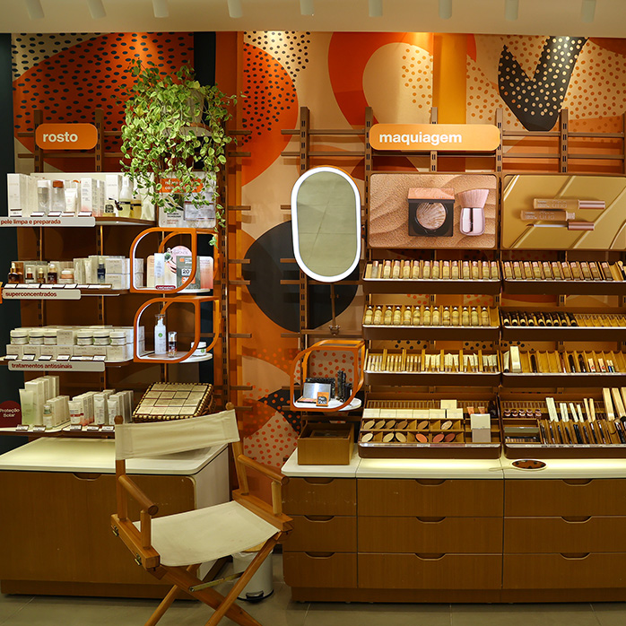 Foto de uma parede de exposição de produtos para rosto e maquiagem em uma loja Natura.