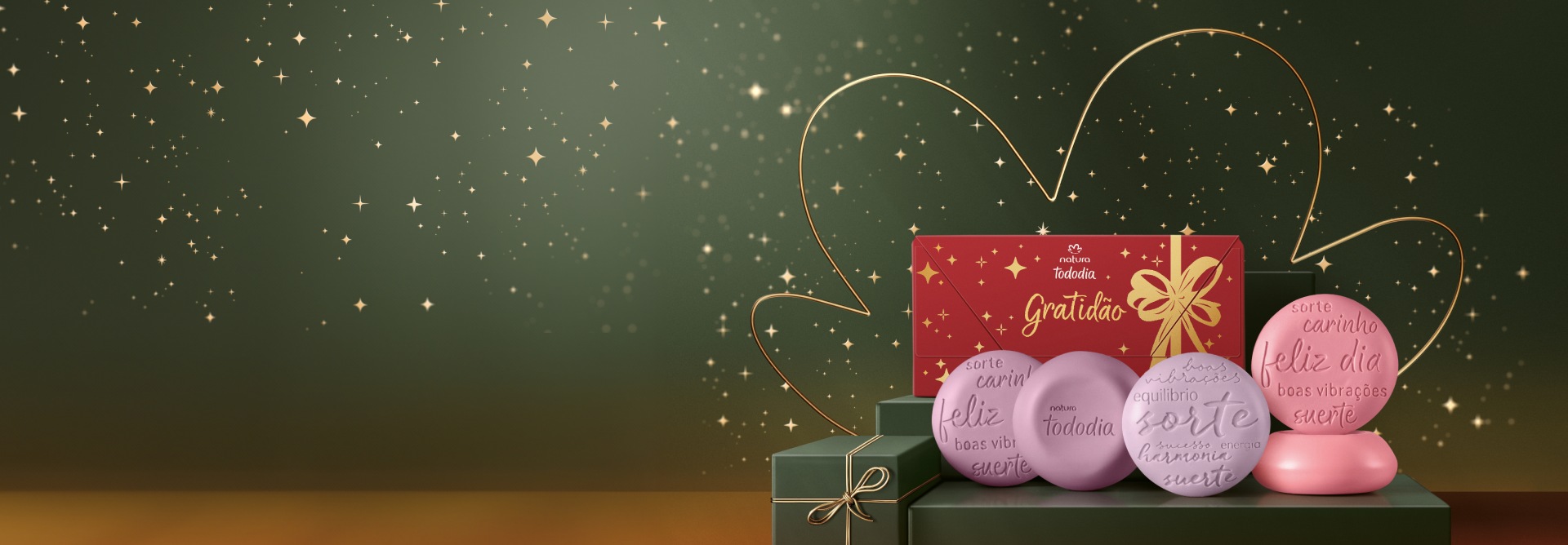 Presente Natura Tododia Sabonetes Gratidão em fundo verde com estrelas douradas. Caixa de sabonetes vermelha com a palavra “Gratidão” em dourado e 5 sabonetes redondos nas cores rosa, roxo e lilás.