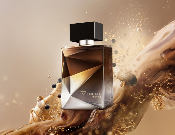 Frasco do Deo Parfum Essencial Desejos Masculino em tons de marrom e prata sobre grãos, gengibre, nozes e demais elementos que remetem aos ingredientes. Fundo marrom.