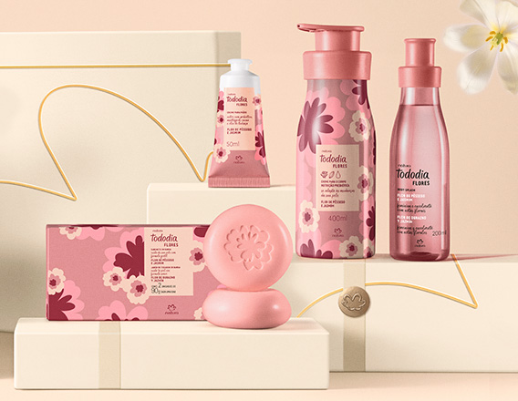 Produtos Natura Tododia sobre caixas presenteáveis em fundo creme com flor branca.