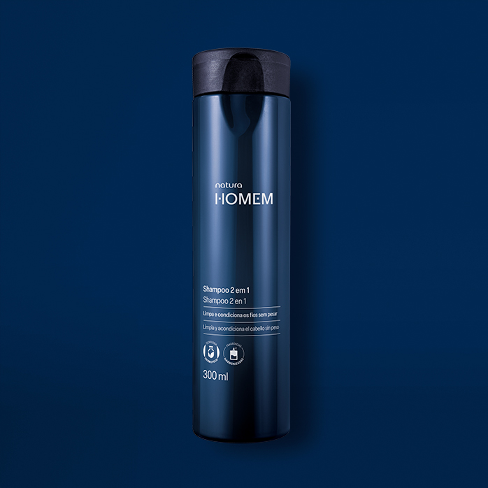 Novo Shampoo 2 em 1 Natura Homem aparece em destaque no centro da tela sobre fundo azul-marinho.