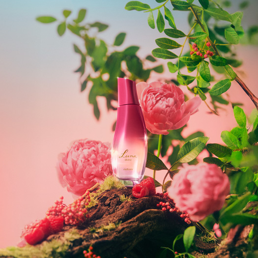 Luna Divina aparece em destaque em meio a flores, folhas e frutos, ingredientes que compõem a fragrância.