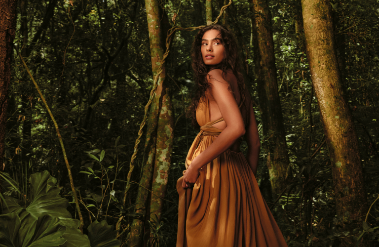 Foto de uma mulher no centro da floresta amazônica, cercada por árvores e plantas