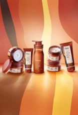 Em fundo em tons de marrom e amarelo, produtos da linha Natura Tododia Jambo Rosa e Flor de Caju: Óleo em Creme, Geleia Desodorante, Loção Corporal, Manteiga Desodorante e Esfoliante Nutritivo.