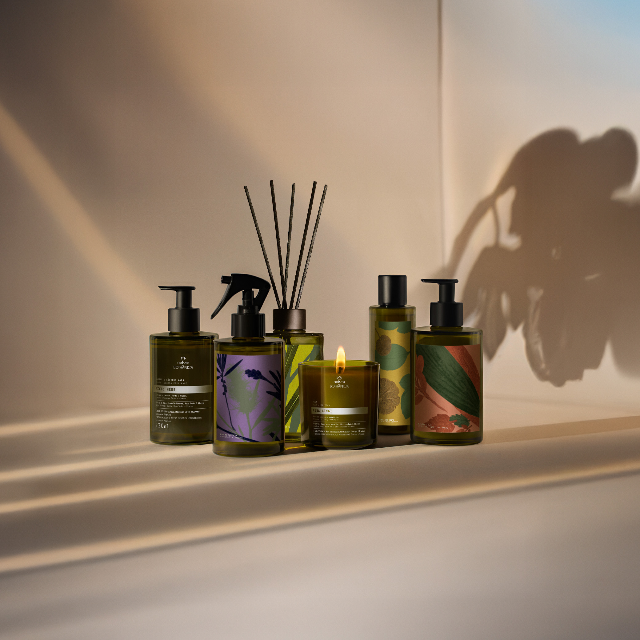 6 produtos Natura Bothânica: sabonete líquido, spray de ambientes, difusor, vela, óleo corporal e hidratante. Embalagens em tom verde escuro com tampas pretas e ilustrações inspiradas em plantas.