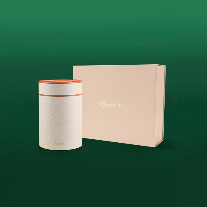 Duas caixas de presente da Natura em formatos diferentes e design elegante. As caixas estão sobre fundo verde.