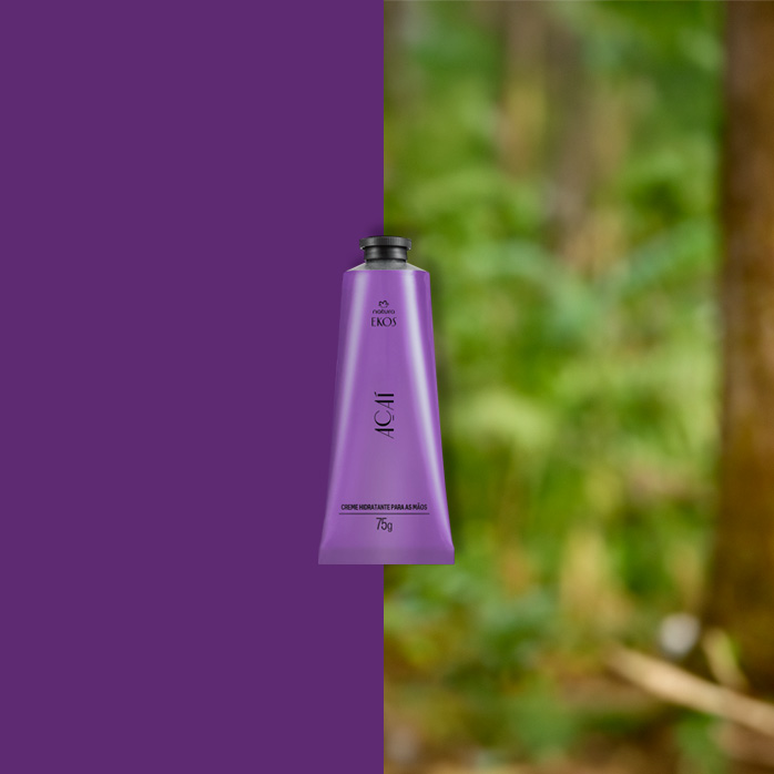 Bisnaga roxa do Creme Hidratante para Mãos Ekos Açaí 75 g centralizada, com metade do fundo roxo e metade mostrando floresta desfocada ao fundo.