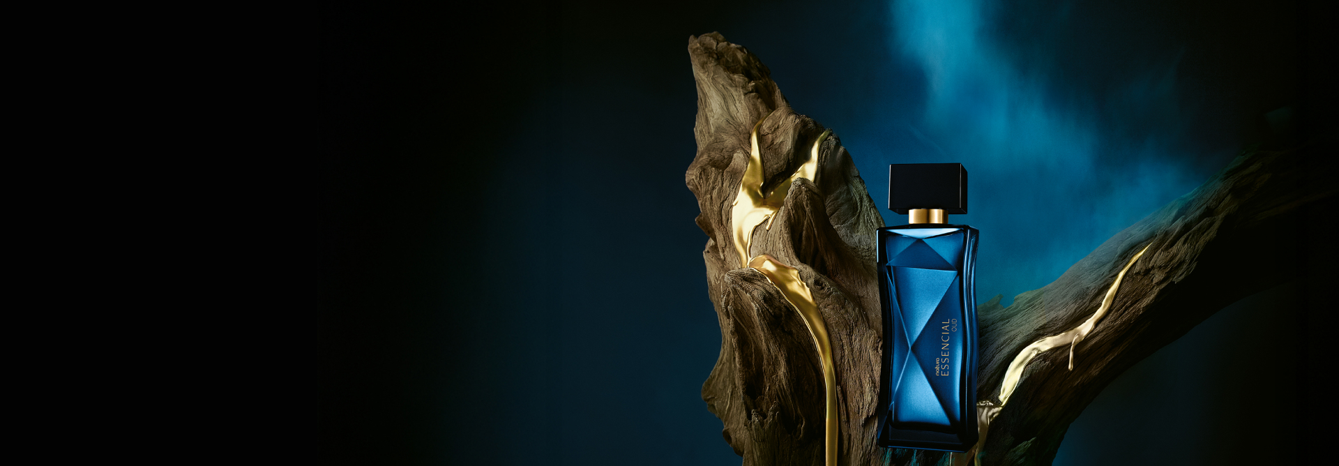 Frasco azul de Natura Essencial Oud sobre tronco de madeira, em fundo azul-escuro.