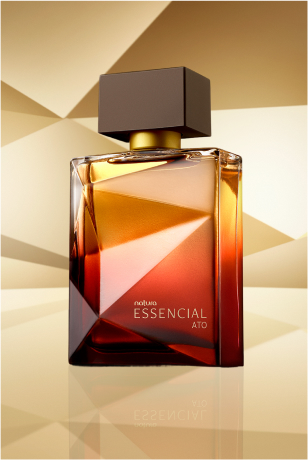 Frasco de Essencial Ato Masculino, em tons de âmbar com tampa preta, aparece em destaque no centro da tela sobre superfície dourada e fundo dourado.