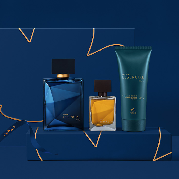 Presente Natura Essencial Oud e Essencial Miniatura aparece em destaque no centro da tela sobre caixas de presentes com fitas azul-marinho e dourado em fundo azul-escuro.