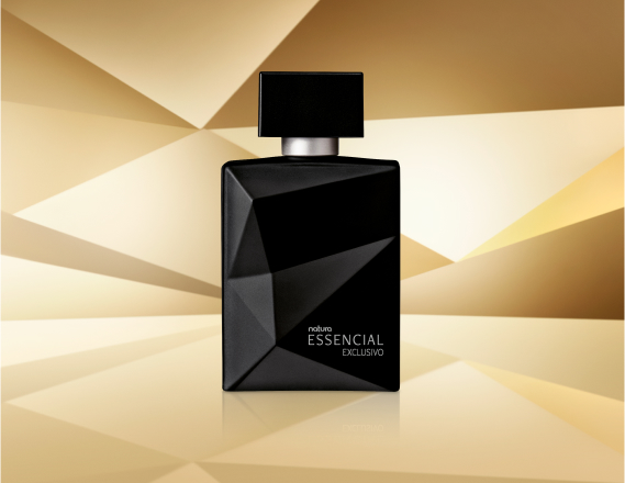 Frasco de Essencial Exclusivo Masculino, em tom de preto, aparece iluminado sobre superfície e fundo dourado-acinzentados.