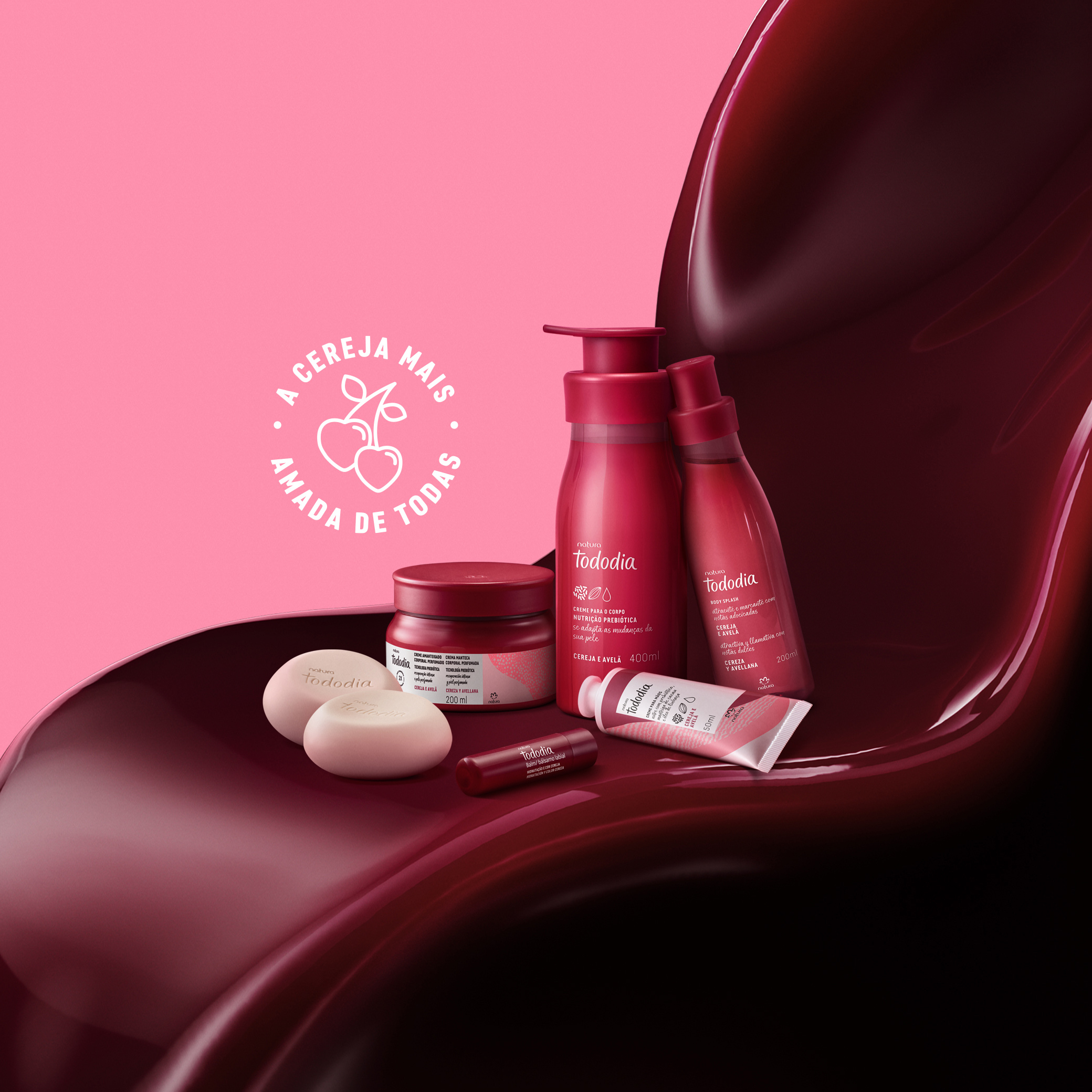 Fundo rosa com selo redondo escrito a cereja mais amada de todas. Em destaque estão 4 produtos de Tododia Cereja e Avelã, incluindo sabonete, batom e cremes, sobre uma textura cremosa na cor cereja.