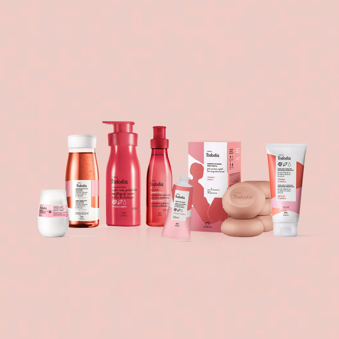 Em fundo rosa-claro, produtos da linha Natura Tododia Tâmara e Canela: Desodorante, Sabonete Líquido, Loção Hidratante, Body Splash, Creme para Mãos, Sabonetes com caixa e Creme Nutritivo para o Corpo.