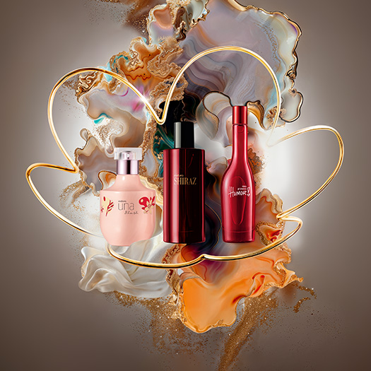 4 Deos Parfum femininos da Natura, sendo Una Artisan, Luna Ilumina, Ilía e Essencial Sentir. Os produtos estão dispostos sobre fundo artístico de tons dourados, brancos e lilás com a flor símbolo da Natura.