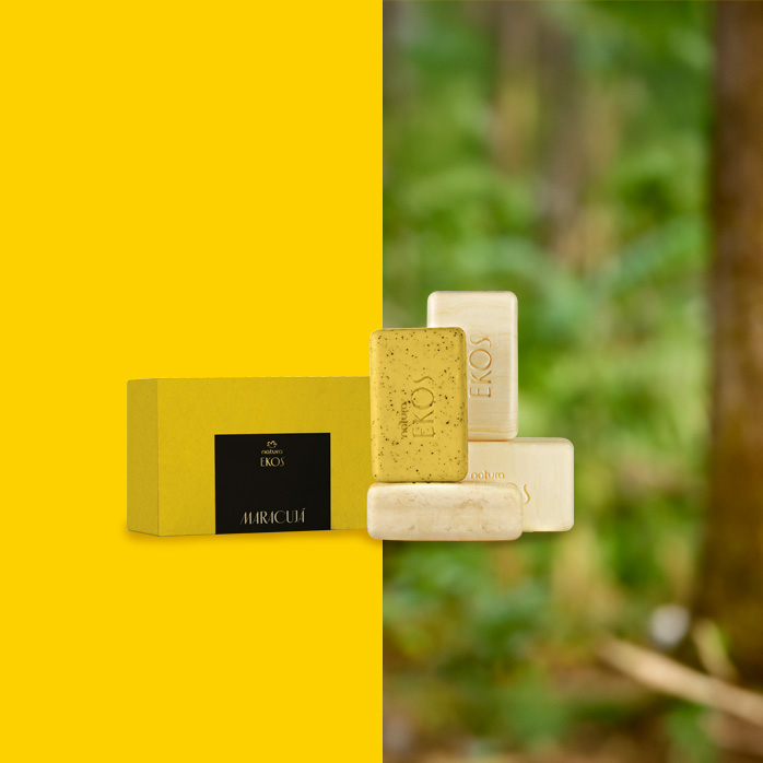 Kit de Sabonete em Barra Cremoso e Esfoliante Ekos Maracujá com embalagens amarelas e barras em tons de amarelo e bege. Fundo dividido entre amarelo vibrante e floresta desfocada ao fundo.