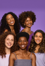 Foto de 5 mulheres com cabelos de diferentes curvaturas de cacheados e crespos,  em fundo roxo.