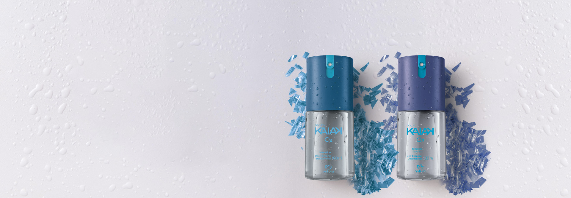 Desodorantes Corporais Kaiak O2 Masculino e Feminino, com frascos transparentes e tampas azuis, destacam-se sobre fundo branco com respingos de água e pedacinhos de plástico azuis.