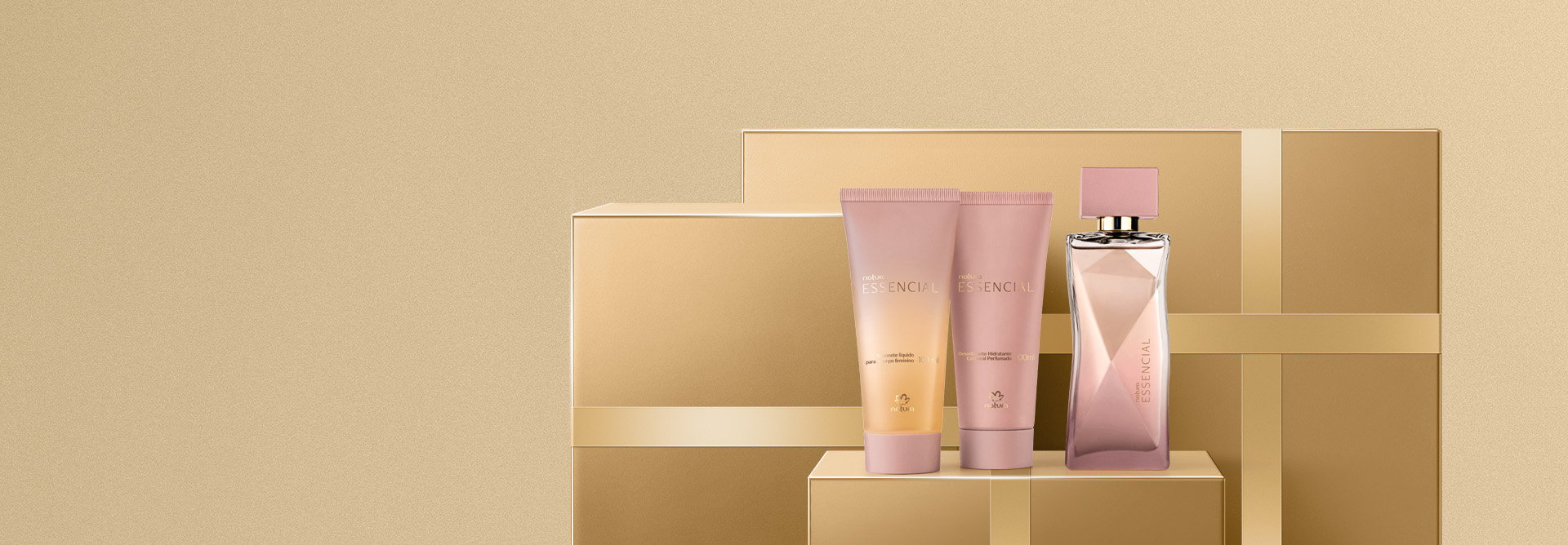 Três produtos Natura Essencial Feminino em tons rosados e dourados, sendo um Sabonete Líquido, um Hidratante Corporal e um Deo Parfum. Os produtos estão sobre caixas de presentes douradas.