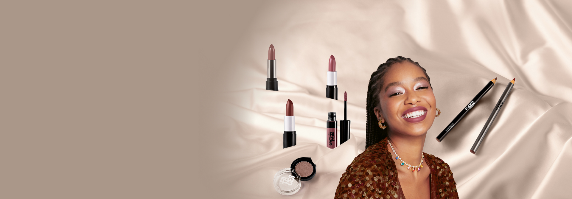 Produtos Natura Faces sobre tecido creme cintilante. Entre os produtos, mulher de tranças, sorrindo e maquiada olha para a câmera.