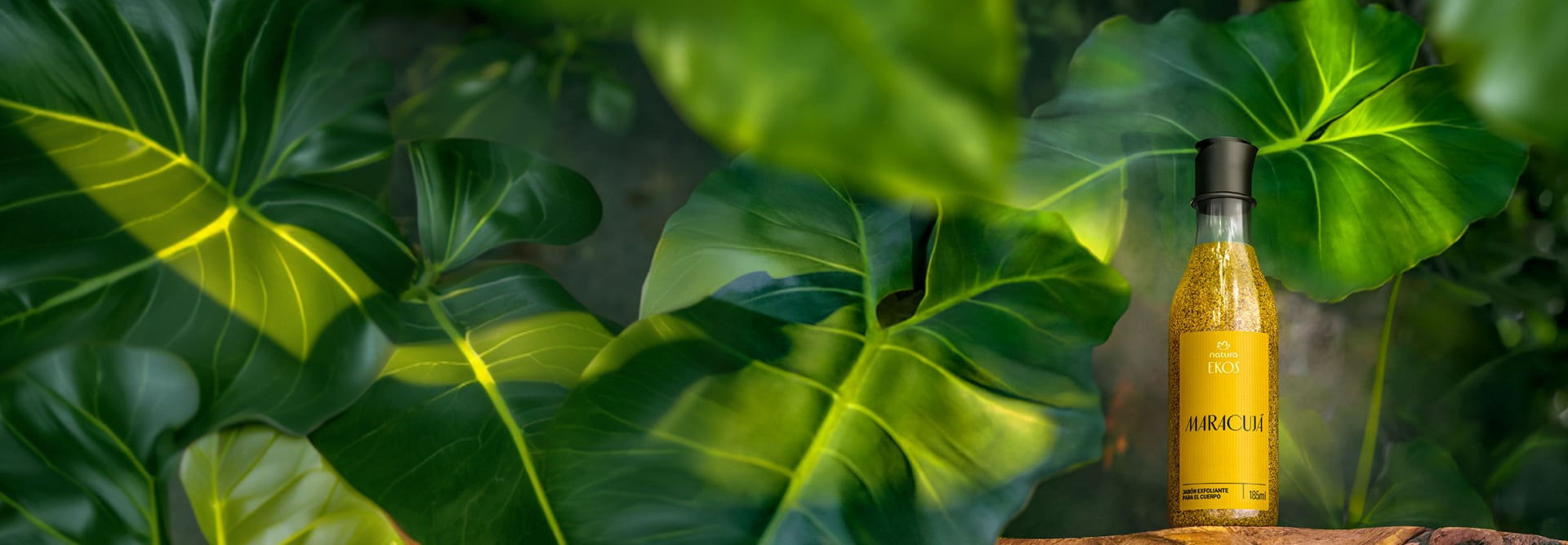 Frasco com conteúdo amarelo de Sabonete Esfoliante Ekos Maracujá sobre madeira em fundo com folhagens verdes.