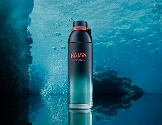 Frasco da fragrância Kaiak Oceano feminino em vidro azul. Fundo marinho com bolhas e reflexo sobre superfície brilhante.