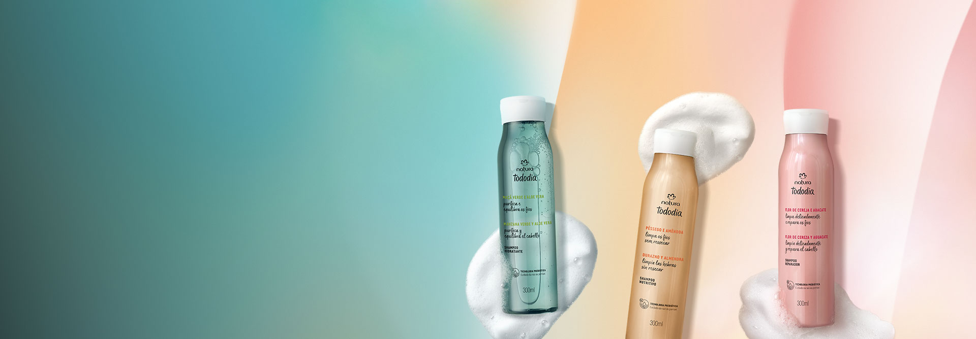 Shampoos Natura Tododia Maçã Verde e Aloe Vera, Pêssego e Amêndoa e Flor de Cereja e Abacate, com frascos verde, amarelo e rosa, destacam-se ao lado de suas texturas em fundo multicolorido.