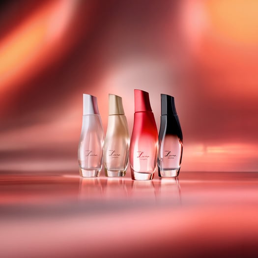 4 frascos de Desodorantes Colônia Luna, 1 rosa de Luna, 1 dourado de Luna Radiante, 1 vermelho de Luna Coragem e 1 degradê preto de Luna Absoluta. Fundo degradê iluminado em tons de vermelho.