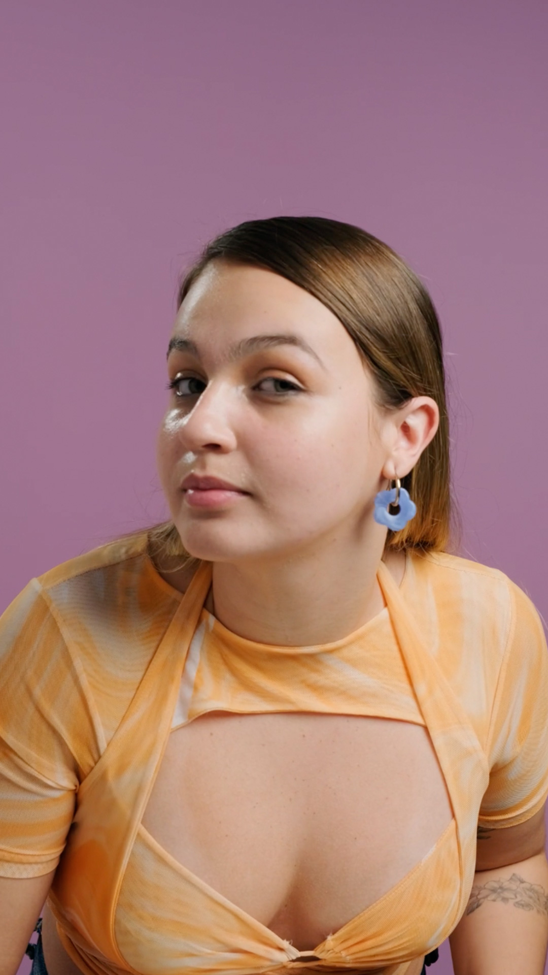 Modelo segura o pote do Bálsamo Demaquilante Faces e aplica no rosto, removendo sua maquiagem. Ela faz movimentos suaves nos olhos, nas maçãs do rosto e, por fim, enxágua com água corrente.