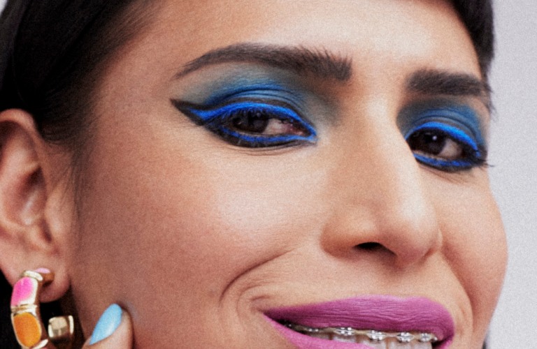 mulher usando delineado azul com a mão no rosto