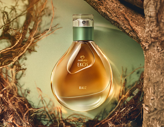 Perfume Natura Ekos Raiz em fundo verde claro com madeiras, folhas e raízes.