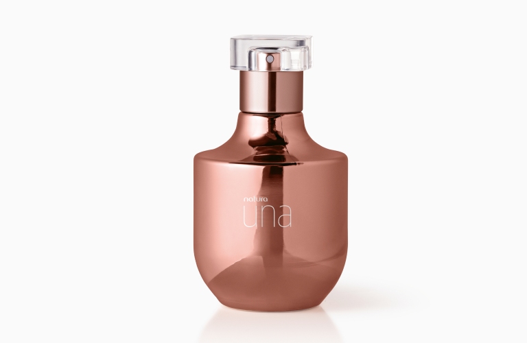 Perfume doce Una em uma imagem com fundo branco. O vidro é rosa e tem uma tampa transparente