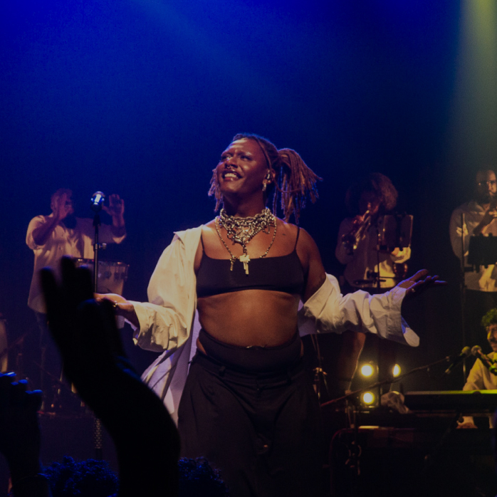 Imagem de uma apresentação musical vibrante com uma cantora no centro do palco, sob luz azul, com a frase "Editais e projetos" em destaque sobreposta.
