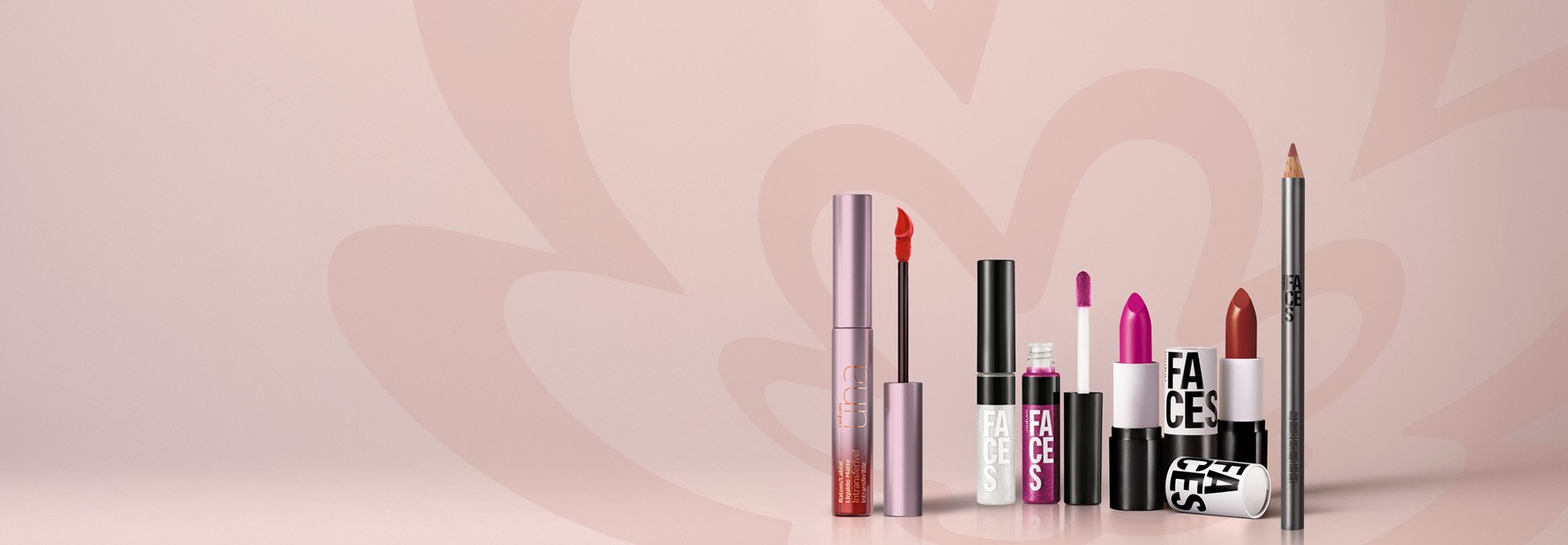 Diversos produtos de Una e Faces, mesclando entre embalagens abertas e fechadas de batons líquidos, cremosos, glosses e lápis labial. Fundo rosa-claro com a flor símbolo da Natura em rosa.