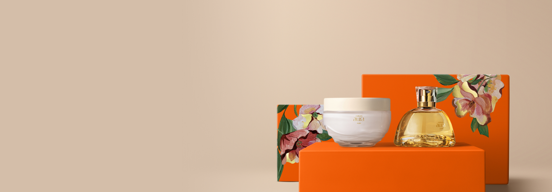 Presente Natura Aura Alba Completo, contendo um Deo Parfum e um Creme Aveludado Corporal. Os itens estão sobre caixas de presentes laranja com estampa de flores em fundo bege.