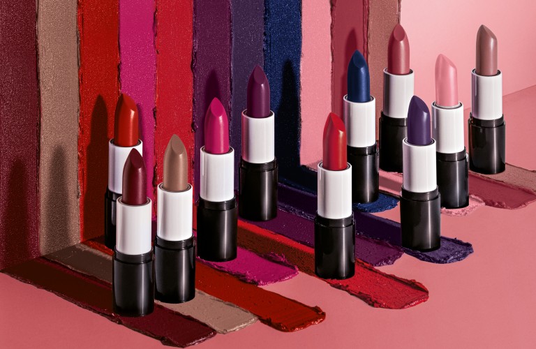 Coleção de batons matte de Natura Faces com várias cores dispostas em um fundo vermelho