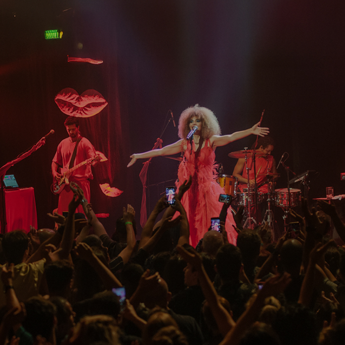 Imagem de um show com uma cantora performando no palco para uma plateia engajada, com a frase "Nosso impacto" destacada no centro.