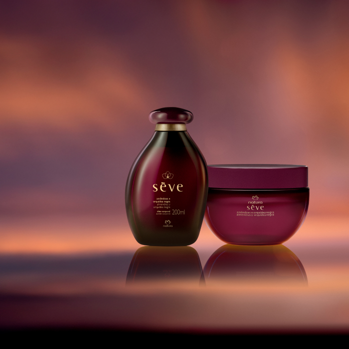 Natura Sève Óleo Desodorante e Creme Desodorante Corporal Perfumado Amêndoas e Orquídea Negra, com frascos em tons de roxo, destacam-se sobre fundo em tons de violeta e laranja.