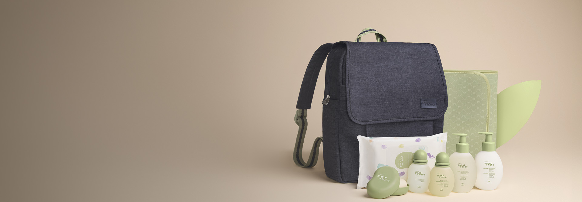 Presente Natura Papai e Bebê com Mochila aparece em destaque na tela com Sabonete em Barra, Shampoo, Condicionador, Colônia, Óleo de Massagem, Lenços Umedecidos, Mochila e Trocador em fundo bege.