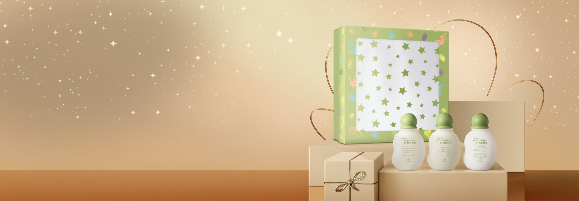 Presente Natura Mamãe e Bebê Miniaturas, com Sabonete Líquido, Loção Hidratante e Água de Colônia, em fundo claro com estrelas e flor da Natura. Frascos brancos com tampa verde e caixa de presente colorida.