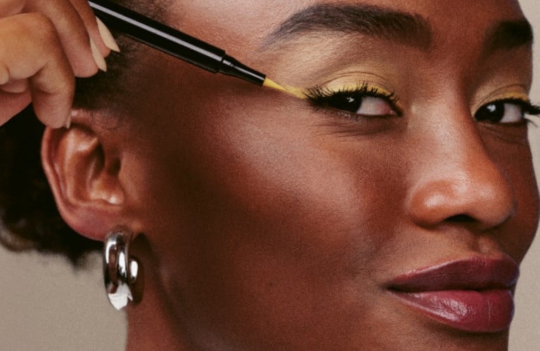 mulher com delineado colorido com a mão no rosto