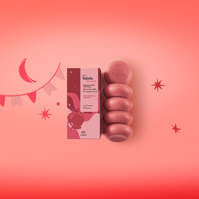 Sabonetes Natura Tododia em fundo em tons de vermelho com ilustrações de estrelas, lua e bandeiras juninas.