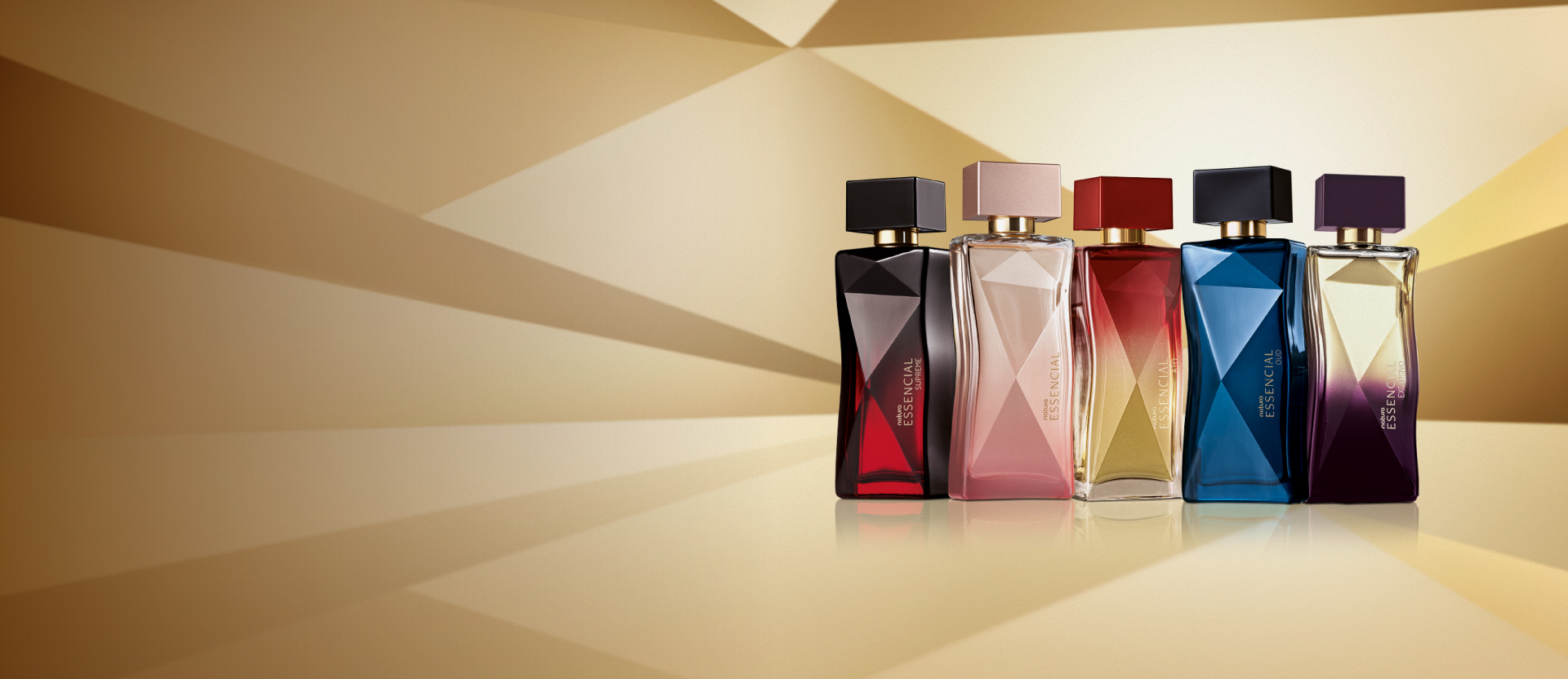 As fragrâncias femininas Essencial Supreme, Essencial, Essencial Ato, Essencial Oud e Essencial Exclusivo em destaque em fundo dourado multifacetado, fazendo alusão ao design dos frascos de Essencial.