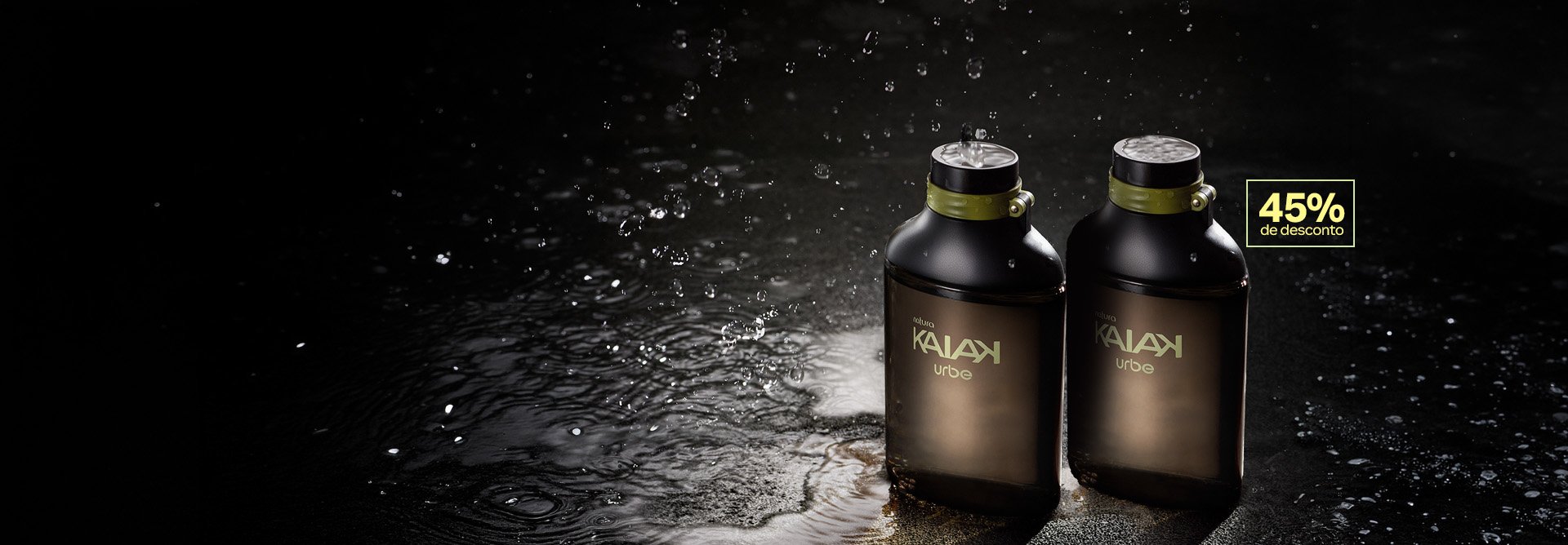 2 frascos verde-acinzentados de Natura Kaiak Urbe Masculino, com tampas pretas e detalhes verdes, destacam-se sobre uma superfície molhada com respingos de água e selo retangular escrito 45% de desconto.