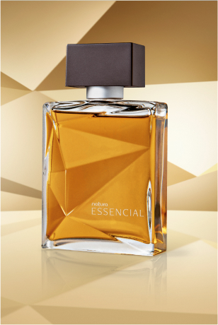 Frasco de Essencial Masculino, em vidro translúcido com fragrância em tons de âmbar e tampa preta, aparece em destaque sobre superfície e fundo em tons de dourado.