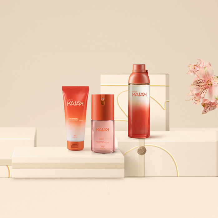 Fragrâncias Natura Kaiak sobre caixas presenteáveis e fundo na cor creme com flores à direita.