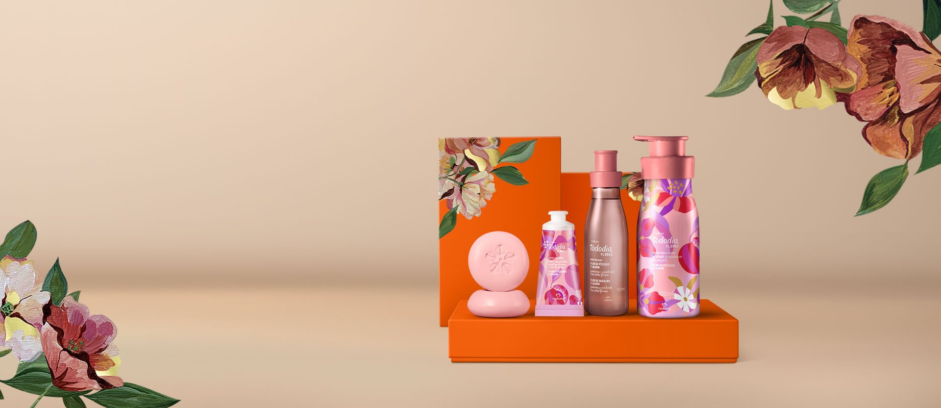 Presente Natura Tododia Flores, com Body Splash, Creme Desodorante Nutritivo para o Corpo, Creme para Mãos e Sabonetes em Barra sobre caixas laranja com ilustrações florais, em fundo bege. 