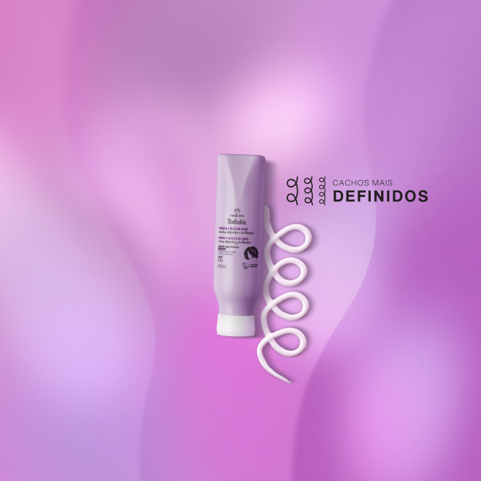 Creme de Pentear Cachos Natura Tododia sobre textura branca do  produto, em fundo roxo, com selo Cachos mais definidos ao lado do produto.