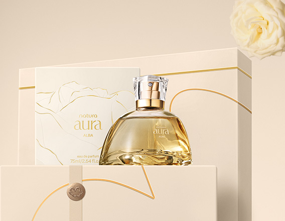 Perfume Natura Aura Alba sobre caixas presenteáveis em fundo creme com rosa branca.