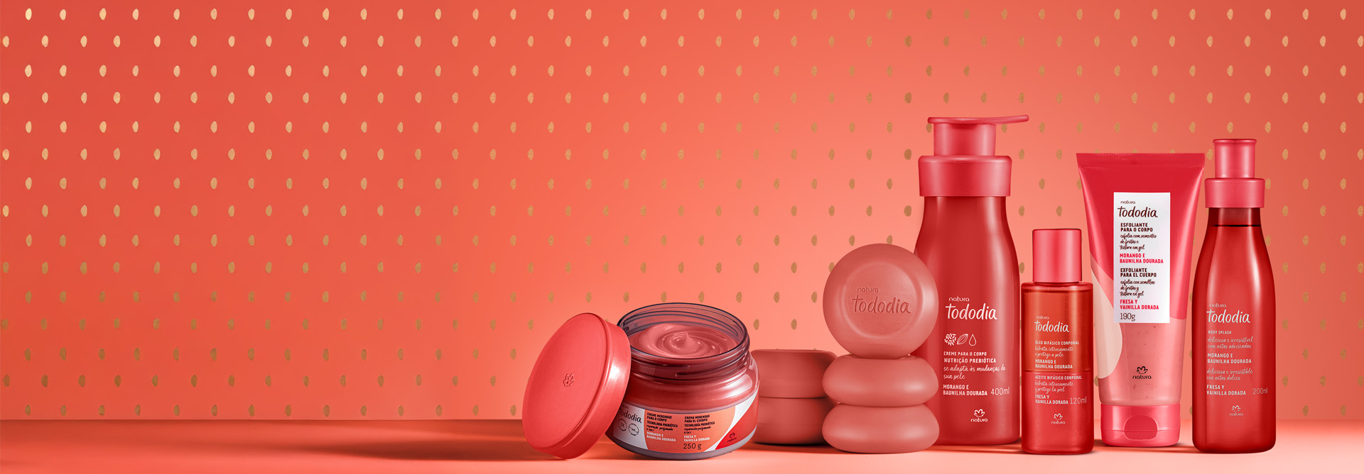 Linha completa de Tododia Morango e Baunilha Dourada em fundo vermelho texturizado, incluindo Creme Merengue, Sabonetes em Barra, Creme para o Corpo, Óleo Bifásico Corporal, Esfoliante para o Corpo e Body Splash.